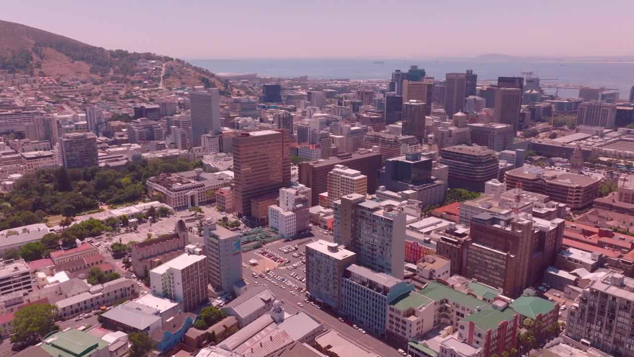 A drone shot slowly orbits around the central city building of cape town and the overall environment of the city