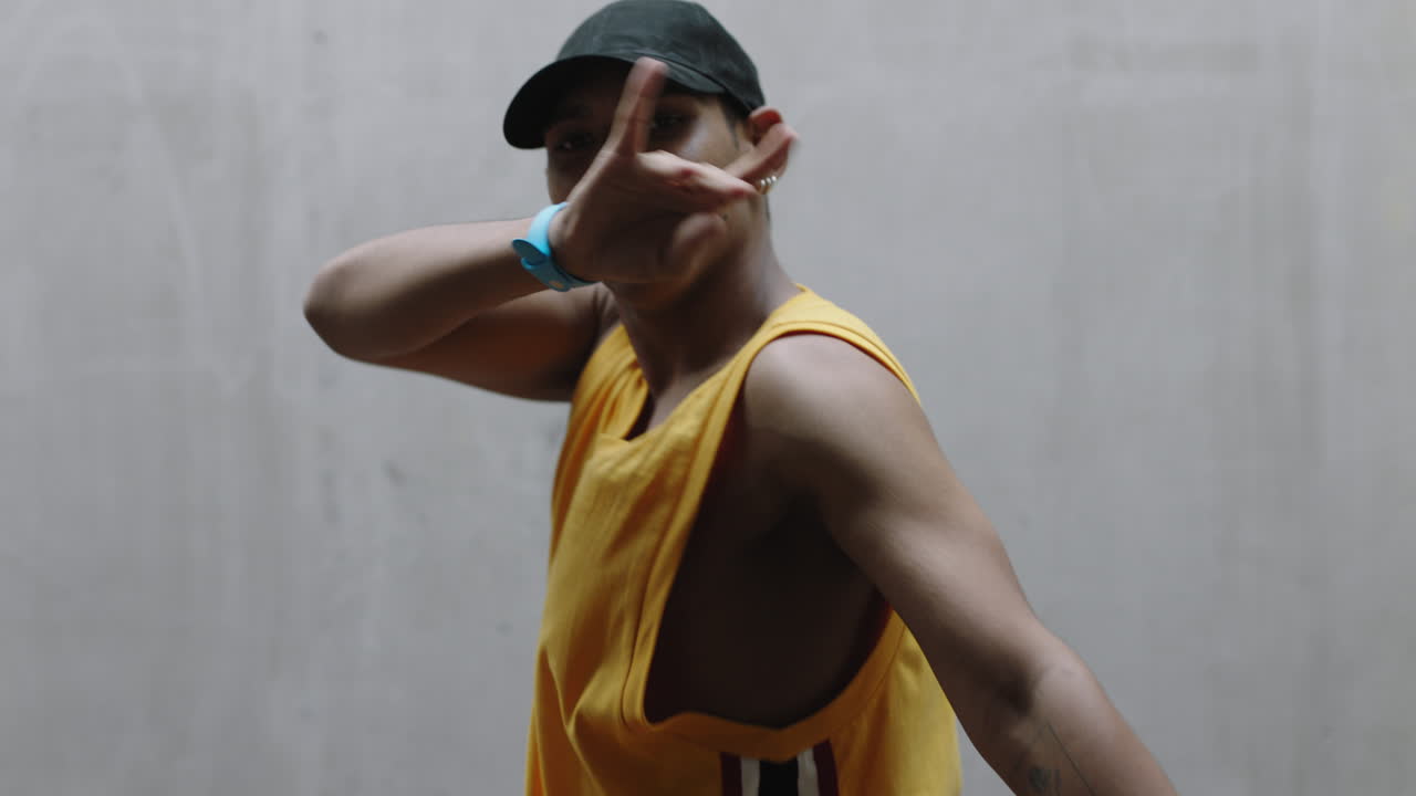 dancing man young happy street dancer performing various freestyle dance moves fit mixed race male practicing in grungy warehouse wearing yellow vest close up