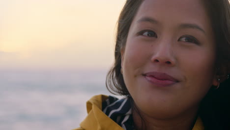 portrait-of-happy-asian-woman-enjoying-peaceful-contemplation-exploring-carefree-lifestyle-relaxing-on-beach-feeling-positive-at-sunrise