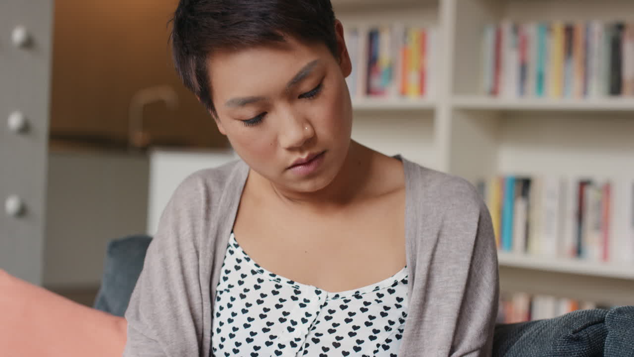 집에서 아름다운 아시아 여성이 스마트폰에서 음악을 듣고 있습니다.