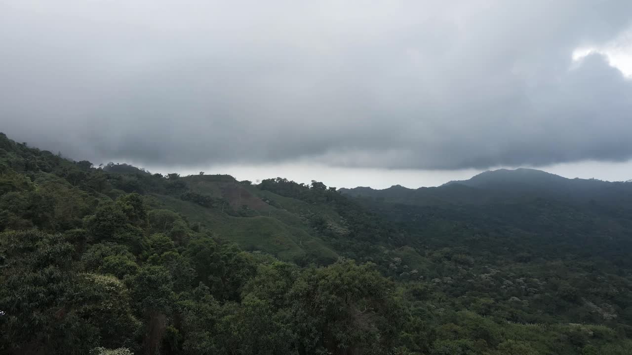 el dron rodea una bandera colombiana con las montañas de la sierra nevada en el fondo, antes de panoramar sobre el suelo boscoso