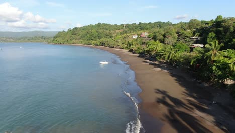 Costa-Rica-beach-drone-view-showing-sea,-shore-and-palm-tree-forest-in-Corcovado-National-Park-on-Osa-Peninsula-on-a-sunny-day-in-the-pacific-ocean