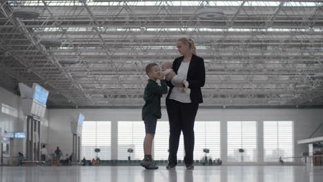 Una-Mujer-Con-Una-Hija-Y-Un-Hijo-En-El-Vestíbulo-Del-Aeropuerto.