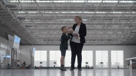 a woman with a baby daughter and a son in an airport hall