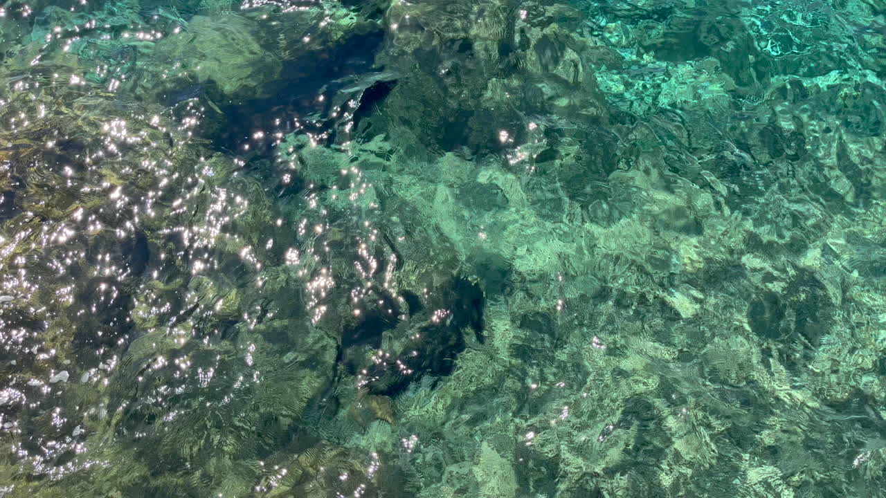 Calm Aegean coastal waters off the coast of Mykonos island with shimmering reflections. Ideal for travel promos, nature docs, wellness content, backgrounds, and relaxation visuals