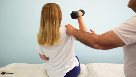 mujer rubia haciendo ejercicios con pesas durante una sesión de fisioterapia