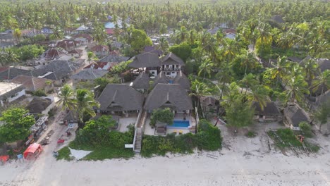 Aerial-approaching-shot-of-luxury-hotel-resort-between-palm-trees-on-Zanzibar,-Africa