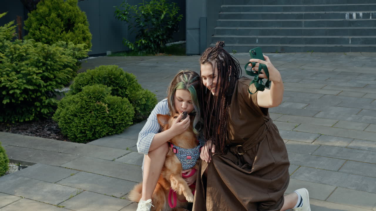 Mother and daughter taking a selfie with their dog outside