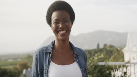 Portrait-of-happy-african-american-woman-smiling-on-sunny-terrace,-slow-motion