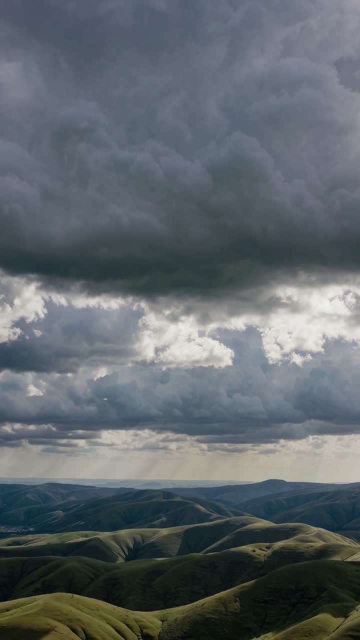 Aerial video still of rolling hills under dramatic, cloudy skies