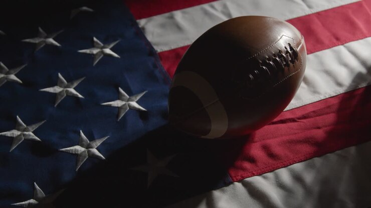 zurückhaltende beleuchtungsstudioaufnahme eines american football mit helm auf sternenbanner-flagge 1