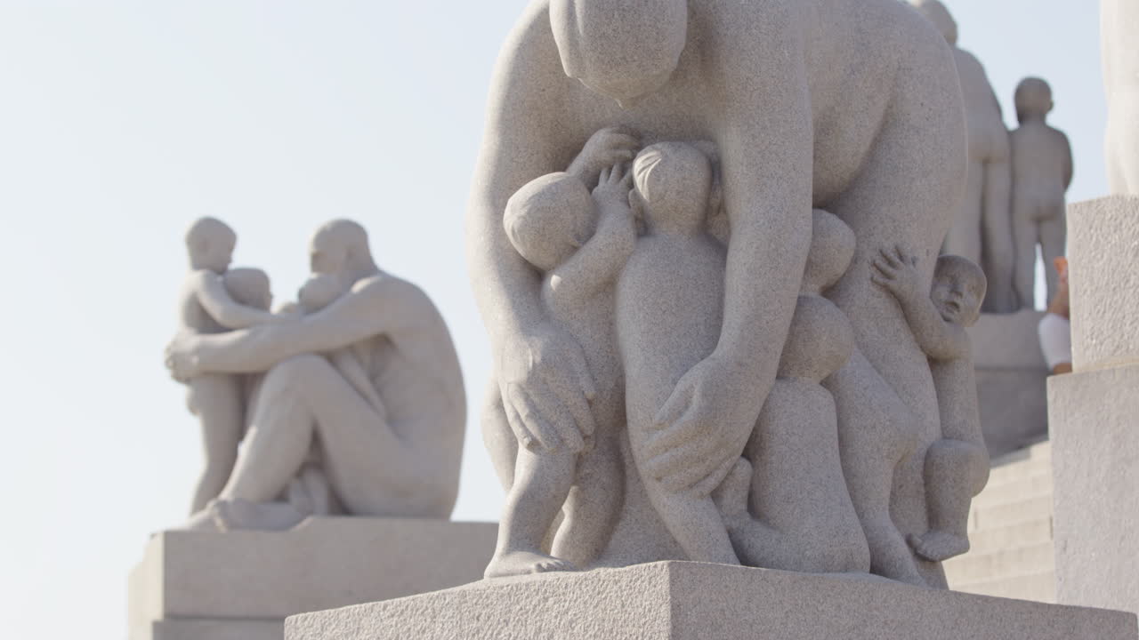 Tourist sightseers walk past sculptures surrounding the Monolith, Vigeland, Oslo