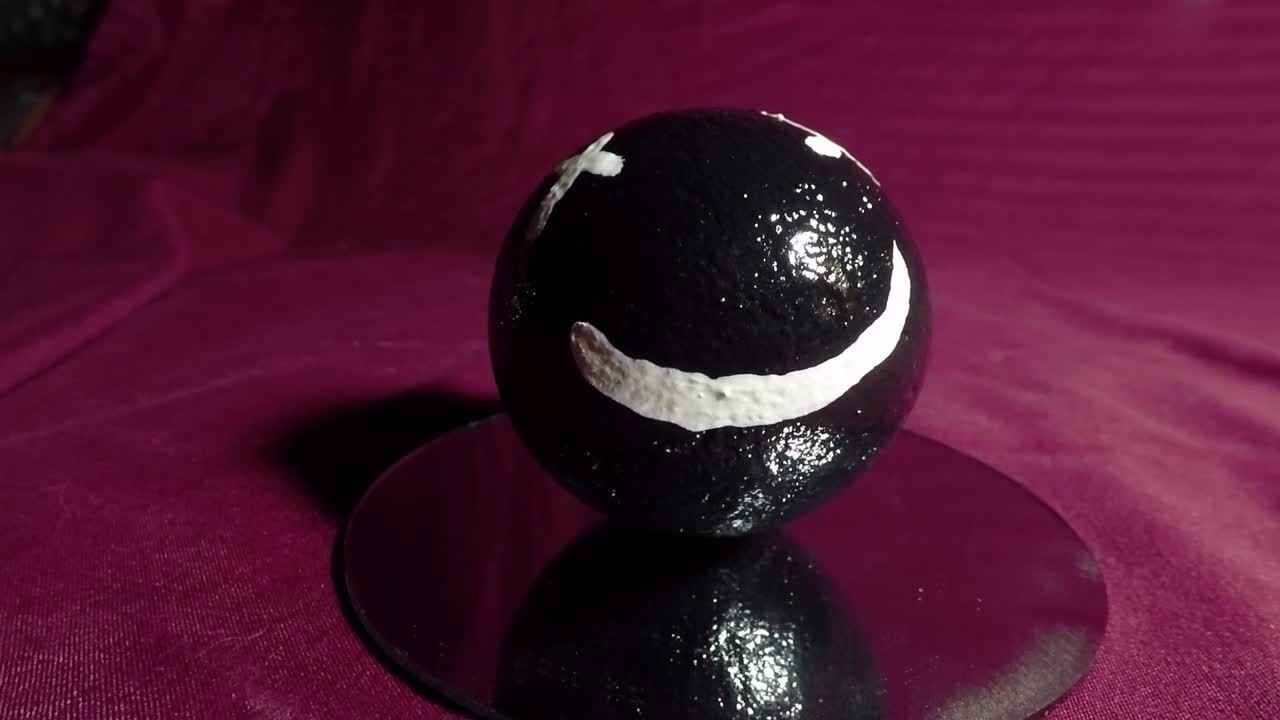 cara feliz en una bola negra hecha de arcilla también conocida como el arte japonés de dorodango