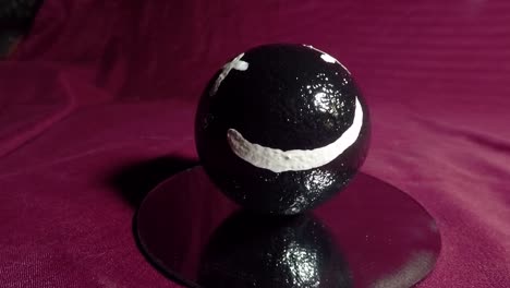 happy face on a black ball make of clay also referred to as the japanese art of dorodango