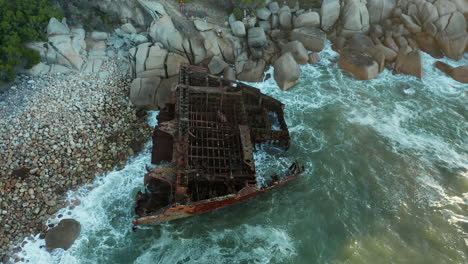 ocean waves crashing against antipolis shipwreck washed ashore in oudekraal beach in cape town, south africa