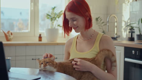 pretty girl gently petting cat and smiling in cozy sunlit kitchen