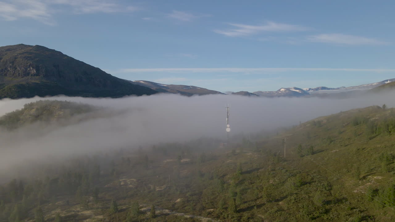 Mountainous Scandinavian countryside with low clouds; drone dolly out