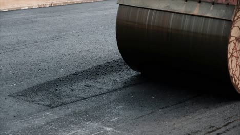 process of asphalting road construction infrastructure by compressing, compacting, leveling and smoothing the asphalt road surface using a tandem roller