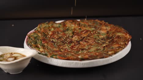 A golden-brown seafood and chive pancake with a crispy outside and chewy texture. Pairs perfectly with a soy dipping sauce. 노릇하게 부친 해산물 부추전, 쫄깃한 식감과 풍미가 입안을 가득 채웁니다. 간장 소스와 함께하면 더욱 깊은 맛을 즐길 수 있습니다
