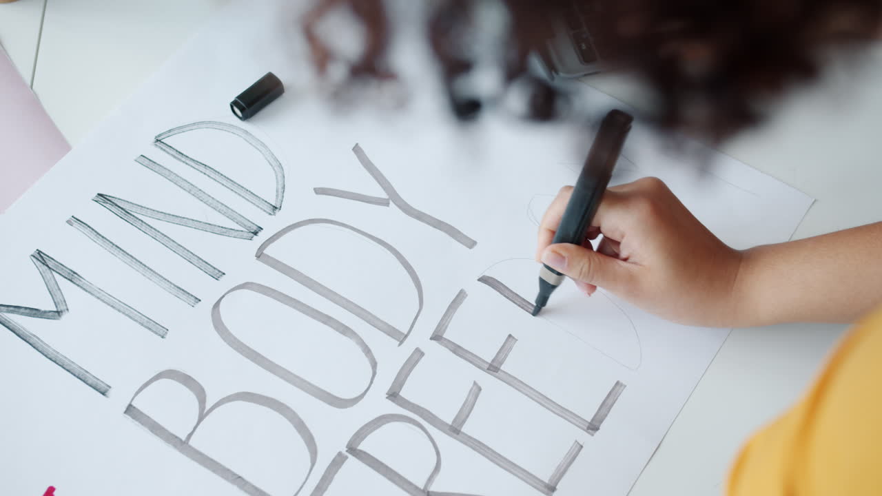 Woman Writing 'Mind Body Free' on a Poster
