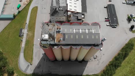 top down aerial sliding view of lantmännen lantbruk industrial crops storage warehouse and large agricultural grains silos located in rural brålanda town vänersborg sweden