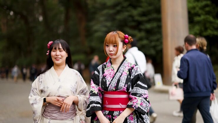 Due amici in yukata tradizionali camminano e parlano all'aperto al Santuario Meiji a Tokyo, Giappone