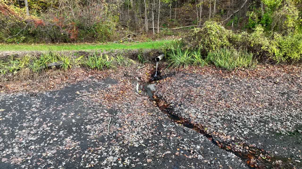 Medium pullback from small pipe and trickle of water into dry empty riverbed