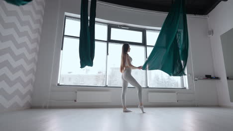 a young woman in slow motion prepares to begin a stretching and yoga class on a hammock. straighten the developing hammock tissue before training