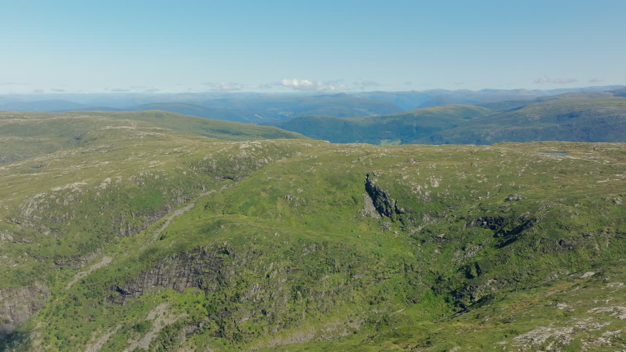 Drone flying forward towards Vidden, capturing sunlit mountain slopes and wide-open landscapes above Bergen