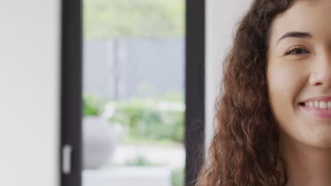 Video-portrait-of-happy-biracial-woman-smiling-to-camera-indoors,-with-copy-space