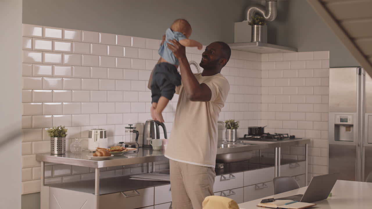 Papà felice che tiene in braccio il suo bambino in cucina