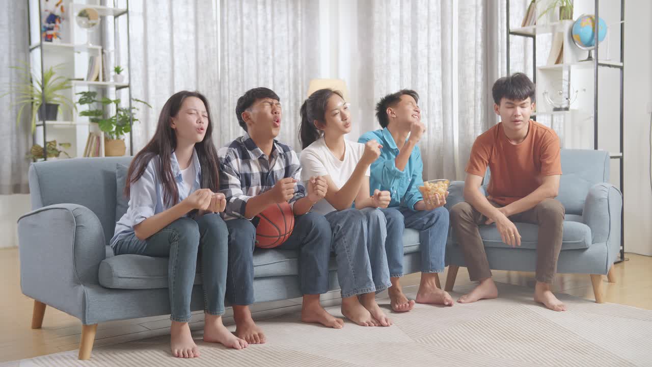 아시아 십대들이 tv에서 농구 경기를 응원하고 지켜보고 집에서 실망합니다.