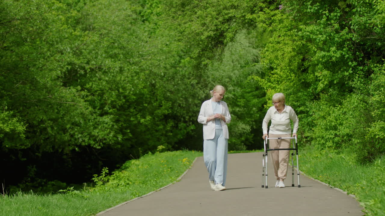 mujer anciana y cuidador caminando en un parque