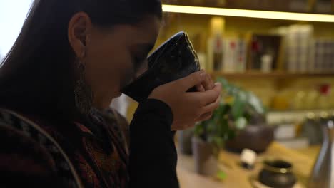 woman enjoying a cup of tea in a cozy shop