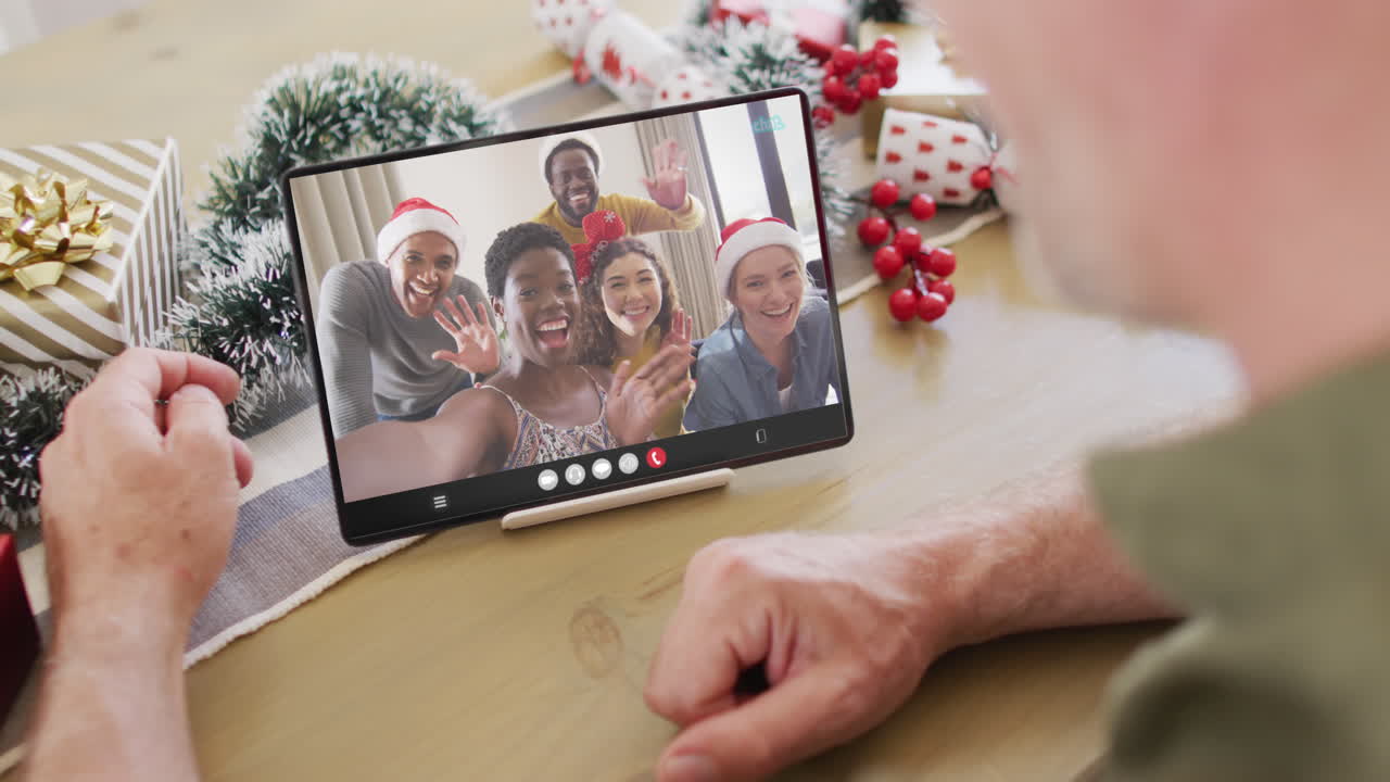 hombre caucásico con decoraciones de navidad teniendo llamada de video de tableta con amigos diversos felices