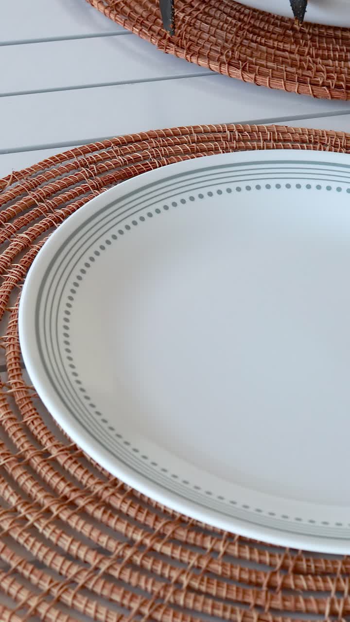 A table is set with fried chicken, plates, and cutlery on a woven placemat in natural lighting