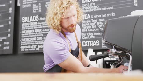 Barista-Masculino-Caucásico-Limpiando-La-Máquina-De-Café-Con-Un-Paño-En-La-Cafetería