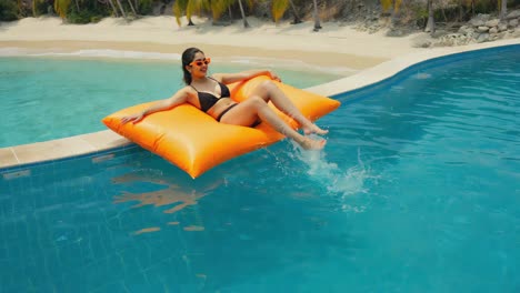 woman relaxing on a floating pad in a pool by the beach
