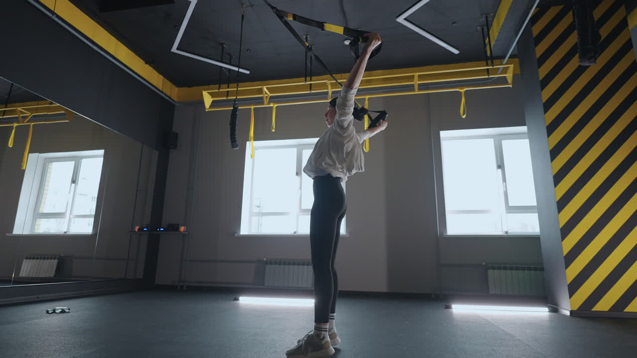 피트니스 체육관에서 trx 장비로 운동하는 여성 건강한 라이프 스타일 강하고 적합한 몸매를 형성하는 매력적인 여성은 체육관의 피트니스 스트으로 코어 abs 훈련을합니다.