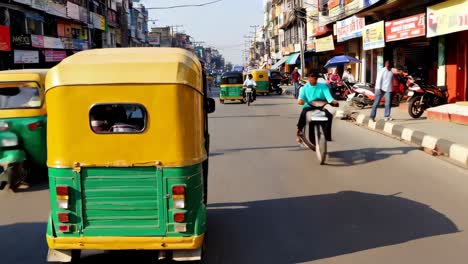 busy city street with auto-rickshaws and motorcycles