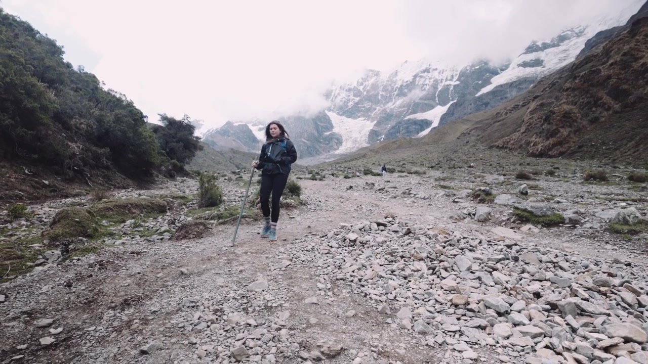 Donna con bastone da trekking che scende dalla collina dopo un'escursione. - campo lungo
