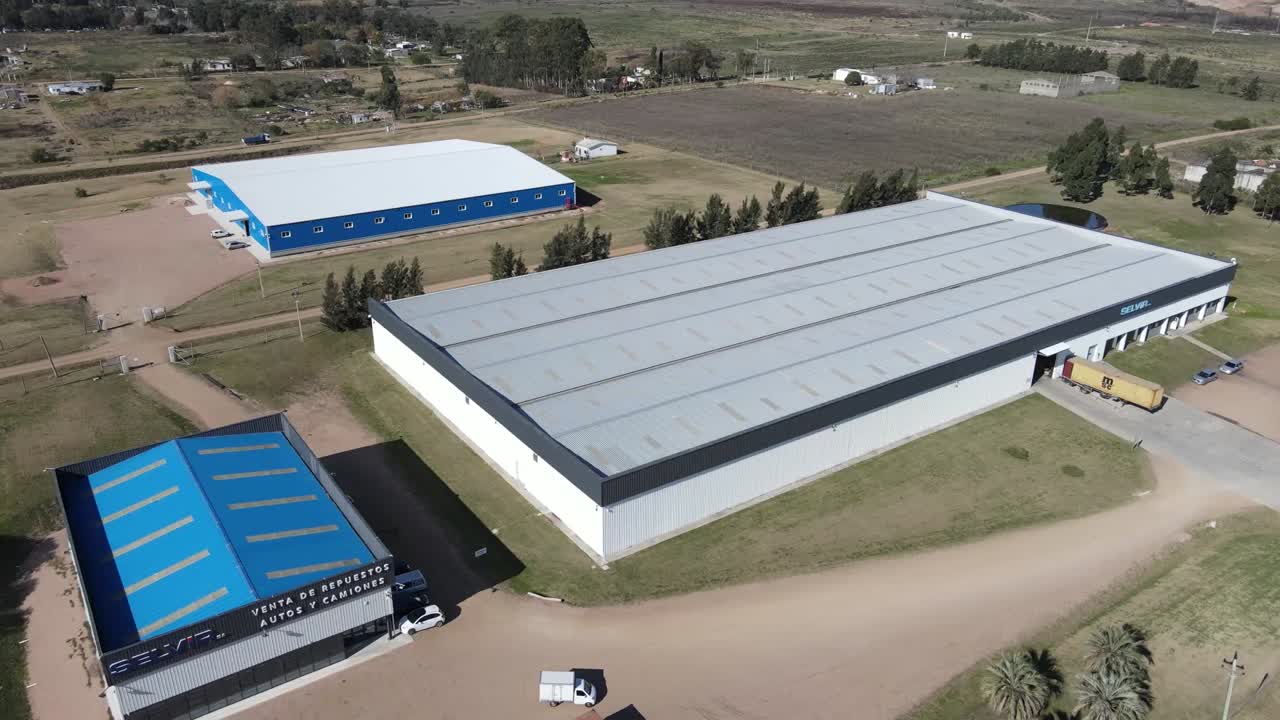 Modern industrial buildings stand in a rural setting, showcasing growth and development in the area