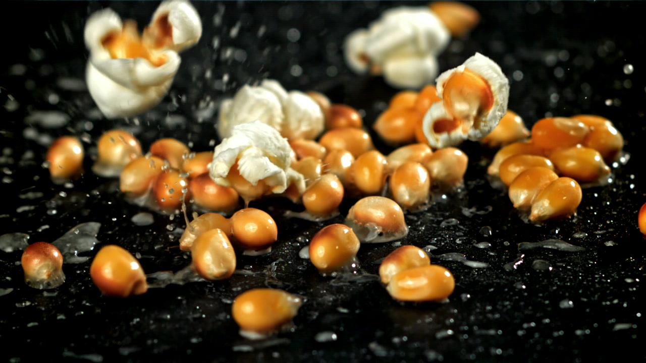 Close-up of Popcorn Kernels Popping on a Black Surface