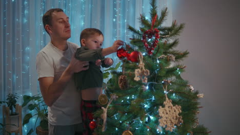 Die-Familie-Schmückt-Gemeinsam-Den-Weihnachtsbaum.-Der-Vater-Ist-Eine-Mutter-Und-Zwei-Kinder-Stellen-Gemeinsam-Weihnachtsbäume-Auf.-Glückliche-Familie-Am-Heiligabend.-Hochwertiges-4K-Filmmaterial