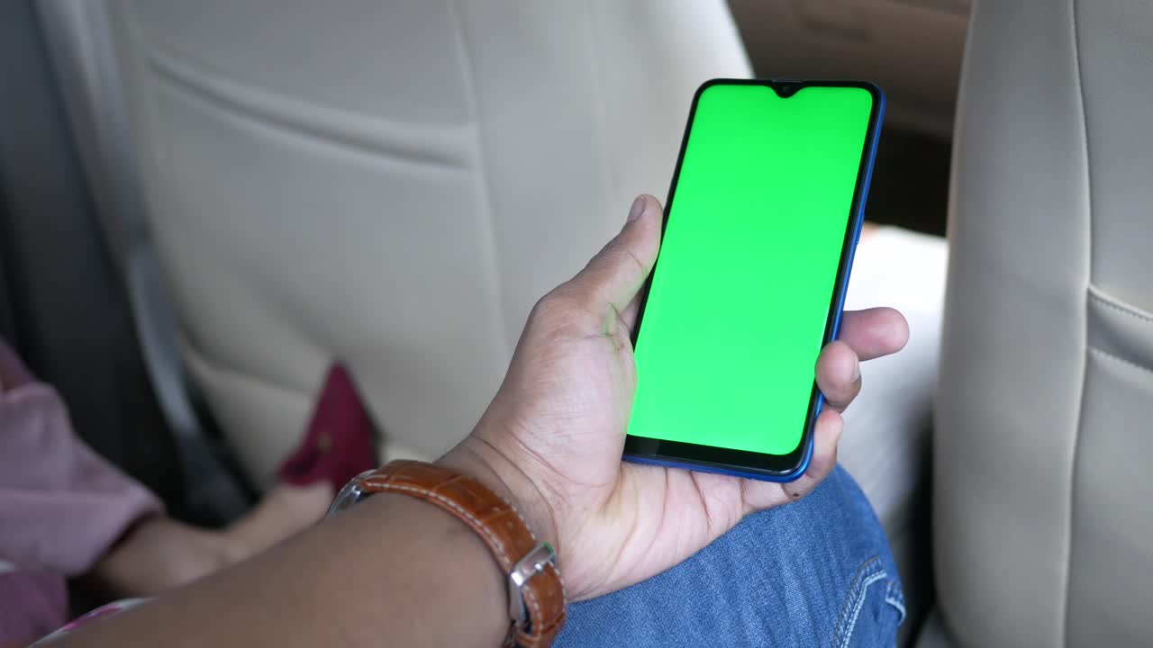 persona sosteniendo un teléfono inteligente con una pantalla verde en un coche