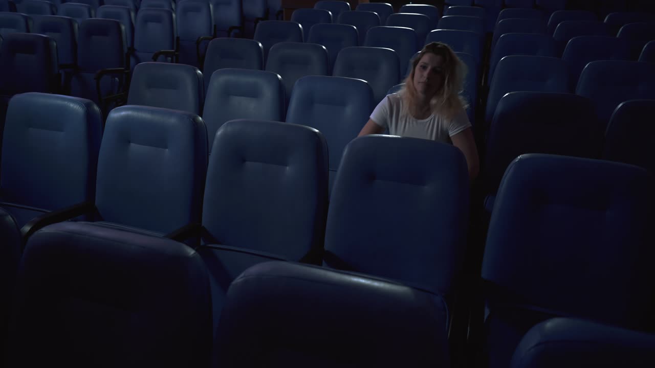 una mujer está viendo una película sola en un cine vacío. cine