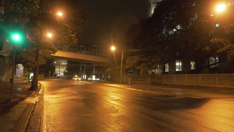 car driving on an empty road with yellow street lights at night - coronavirus pandemic - sydney, nsw, australia. - wide shot