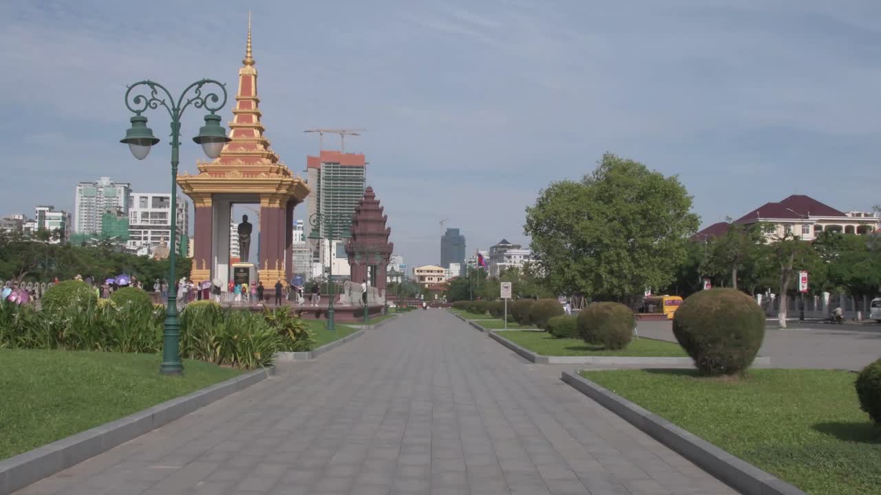 fotografía estática de una carretera en phnom penh con un monumento y una bandera camboyana en el fondo, asia