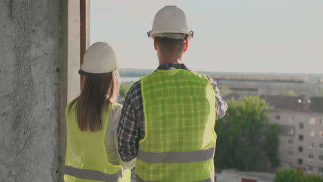 couple-of-engineer-or-technician-man-and-woman-with-safety-helmet-holding-mobile-radio-phone-planning-about-building-plan-to-greeting-start-up-project-in-construction-site-building-industry-concept