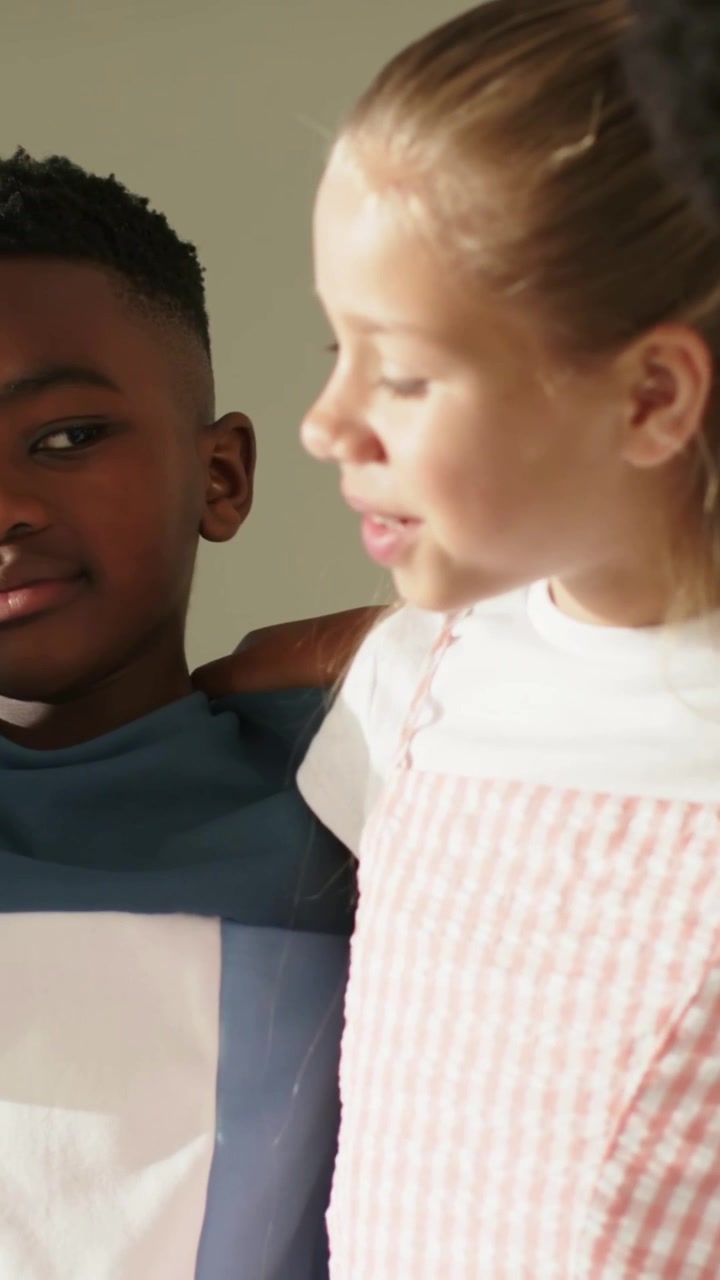 Vertical video: Camera shifting left kids linking arms to pose at school in pink dress and blue sh
